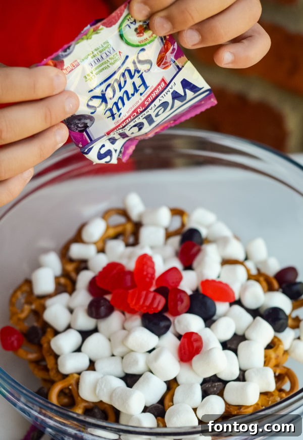 Kids actively helping prepare the No-Bake Sweet & Salty Snack Mix, emphasizing its ease and fun factor.