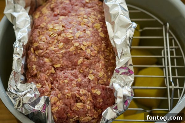 Cooked Ninja Foodi meatloaf, ready for broiling with sauce