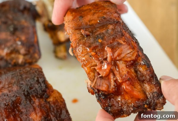 Barbecue sauce being brushed onto cooked Ninja Foodi Ribs