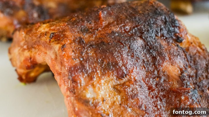 Perfectly cooked, tender Ninja Foodi Baby Back Ribs slathered in barbecue sauce, garnished with fresh herbs.