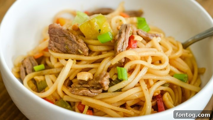 A vibrant plate of Easy Beef Pad Thai featuring tender rice noodles, succulent beef, and fresh bean sprouts and lime wedges.