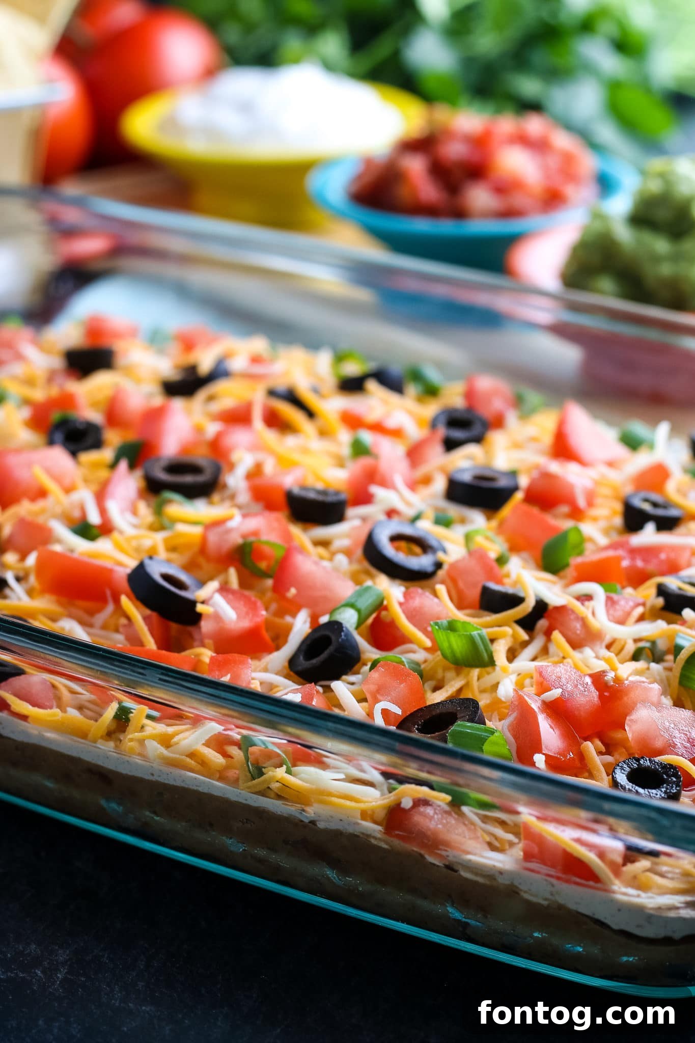 A colorful and appetizing layered taco dip with a spoon