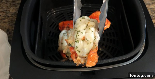Ninja Foodi Grill basket with lobster tails placed inside, coated in garlic butter.