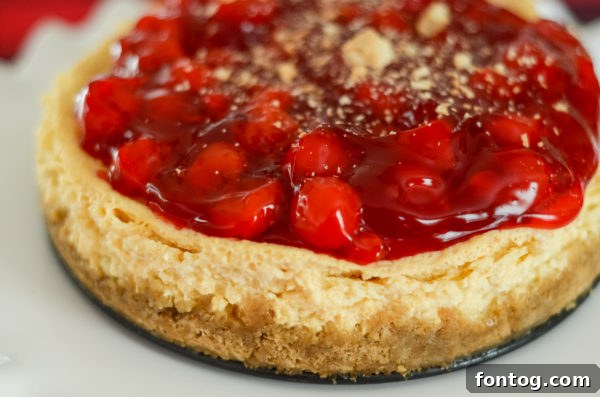 Close-up of a slice of Ninja Foodi Cherry Cheesecake on a plate, showing its creamy texture and the graham cracker crust.