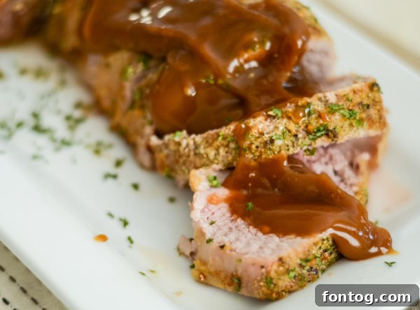 A perfectly cooked, sliced pork tenderloin, garnished and ready to serve.
