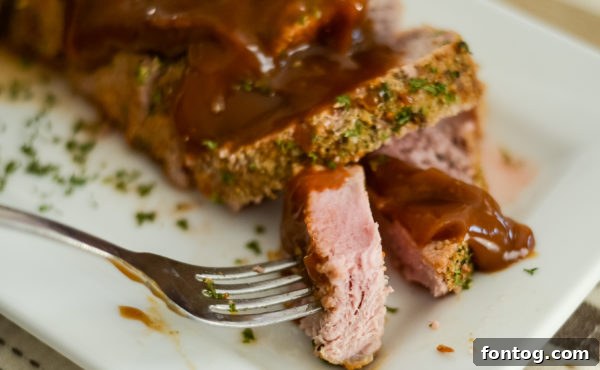 Close-up of a golden-brown pork tenderloin, sliced and ready to serve.