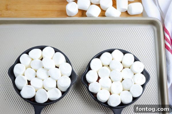 Effortless S'mores Treat 4 Assembling S'mores Dip with marshmallows placed over melted chocolate