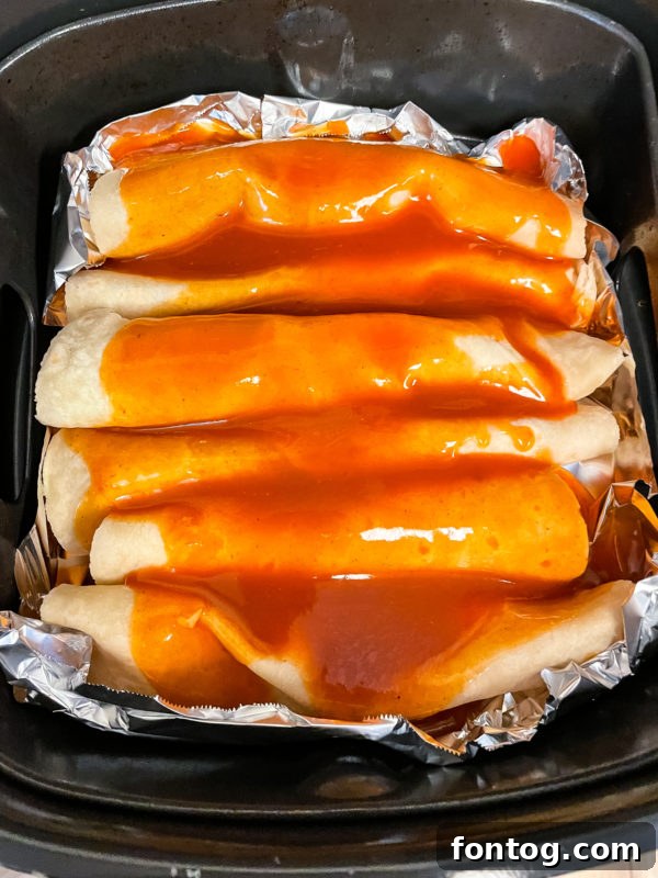 Ninja Foodi Chicken Enchiladas topped with sauce and cheese, ready for cooking.