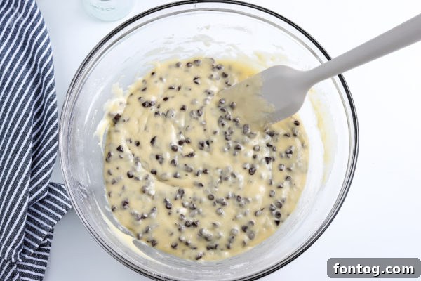 A bowl of gluten-free chocolate chip muffin batter with chocolate chips mixed in.