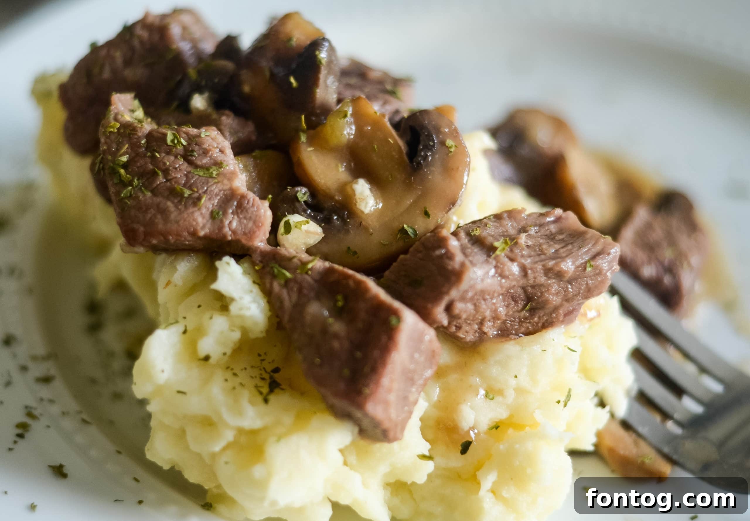 Ninja Foodi Beef Tips plated with mashed potatoes and garnish