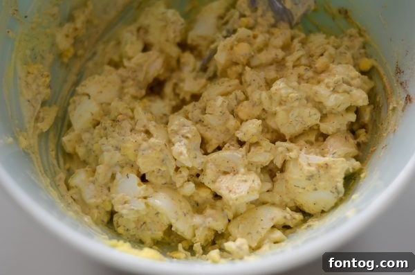 Ninja Foodi egg salad served cold on a sandwich, garnished with fresh herbs