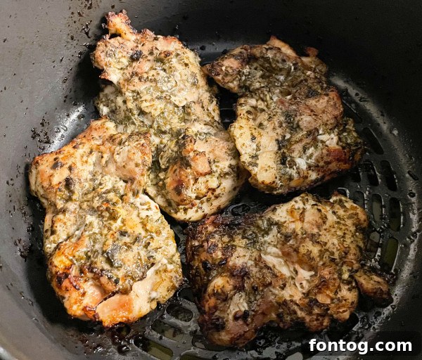 Raw boneless skinless chicken thighs coated generously with pesto sauce