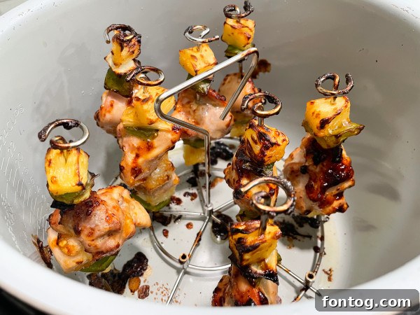 Assembling Chicken and Vegetable Skewers: Raw chicken pieces, diced green pepper, onion, and pineapple chunks neatly threaded onto metal skewers.
