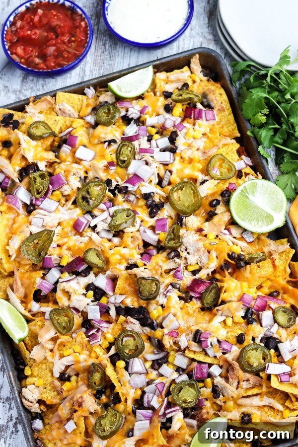 A close-up of a skillet filled with perfectly melted, fully loaded smoked nachos, ready for scooping.