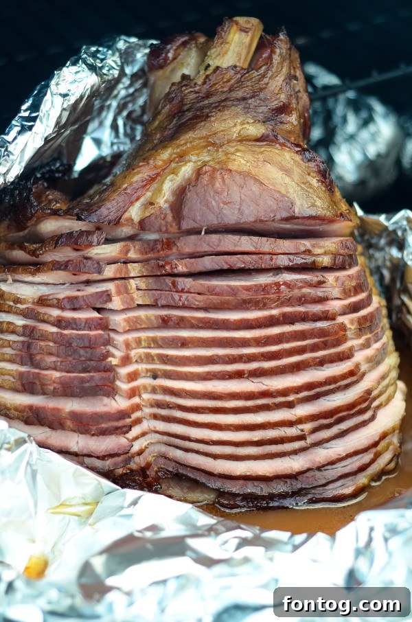 Digital meat thermometer accurately measuring the internal temperature of a ham on a pellet grill.