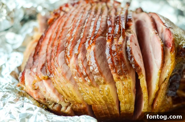 A perfectly glazed ham, glistening with apple cider glaze, ready to be sliced.