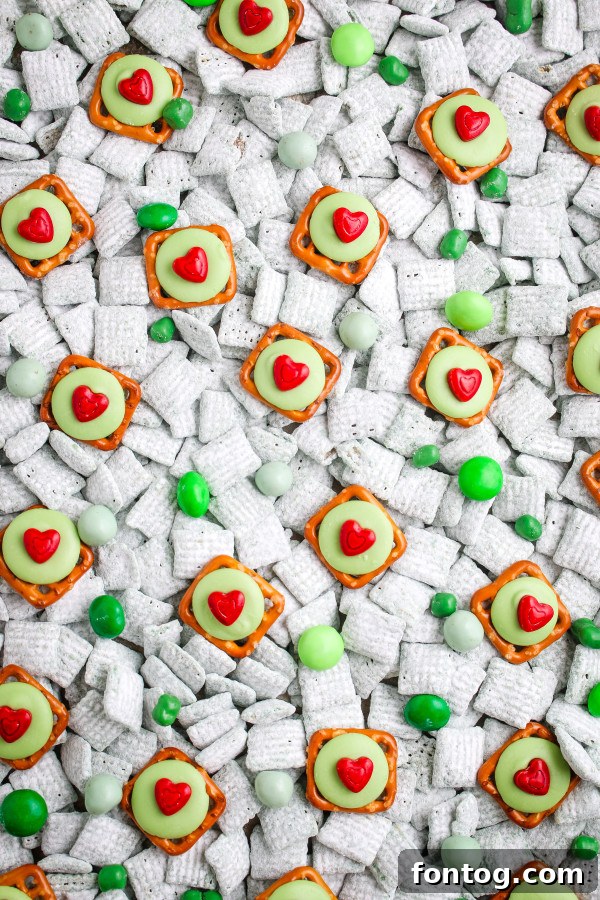 A close-up shot of Grinch Pretzel Bites, highlighting the texture of the pretzel and the melted candy, with a red heart in the center, on a green backdrop.