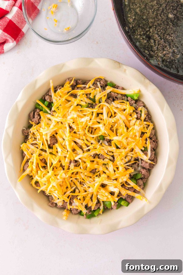 Homestyle Cheeseburger Pie 7 Layering shredded cheddar cheese into the gluten-free cheeseburger pie