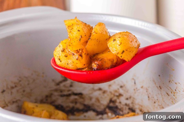 Slow cooker filled with potatoes being stirred