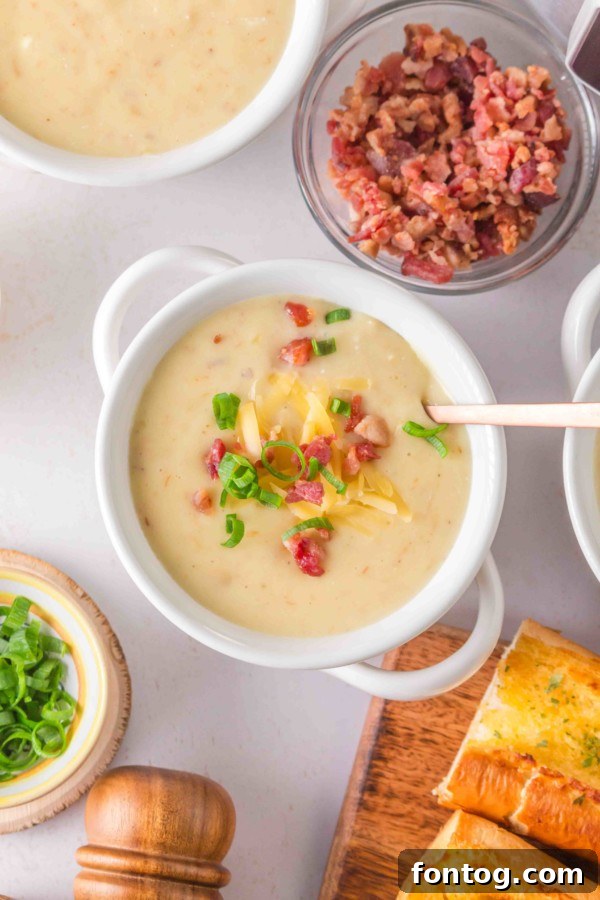 A bowl of gluten-free slow cooker baked potato soup topped with cheese and bacon bits