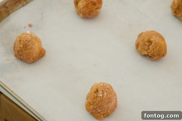 Scoops of raw gluten-free pumpkin spice cookie dough, ready for baking, on a parchment-lined sheet.