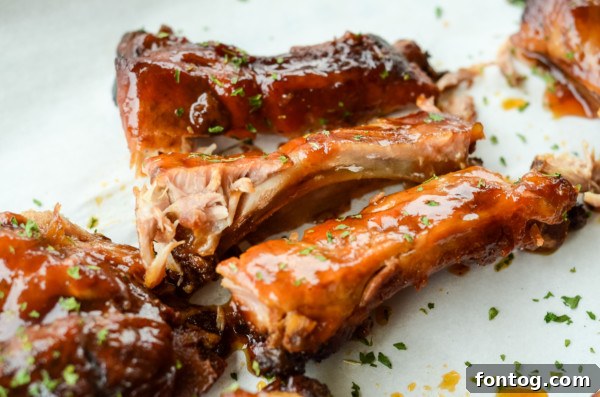 Close-up of a rack of baby back ribs, beautifully cooked with apple BBQ sauce, reflecting light.