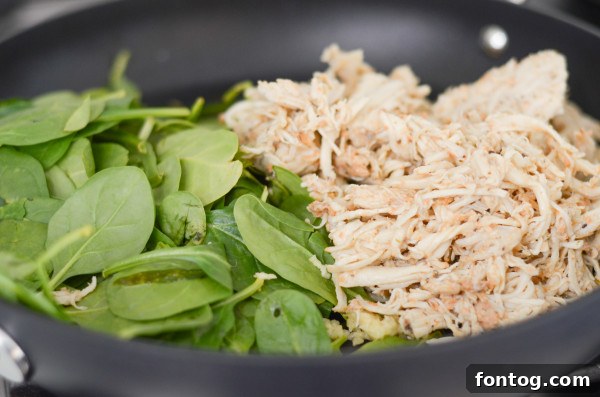 wilted spinach and cooked chicken in a skillet