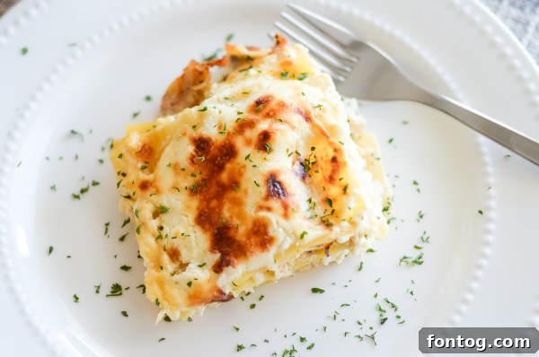 a slice of gluten free garlic chicken lasagna on a plate, garnished with parsley
