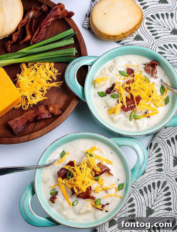 A bowl of pressure cooker potato soup, generously topped with shredded cheese, bacon bits, and green onions, served on a rustic wooden board.
