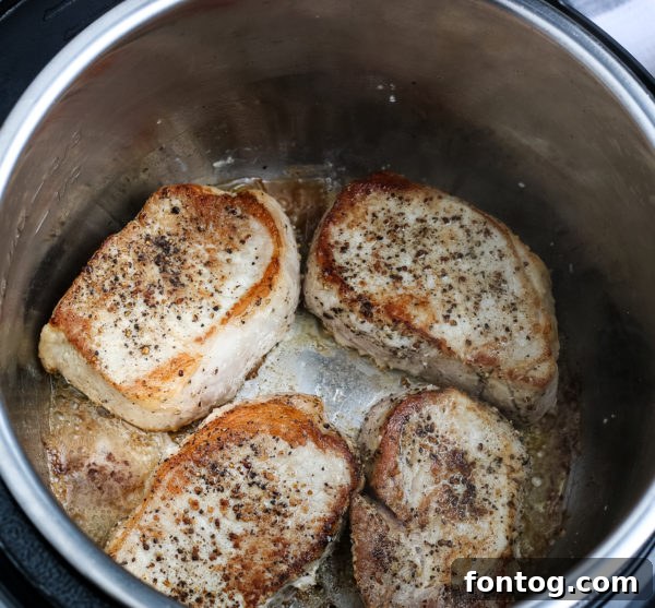 Ingredients for pressure cooker pork chops with gravy being seared in the pot