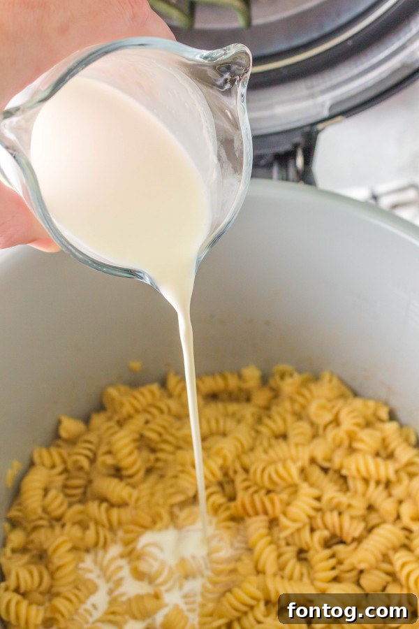 Melting cheese and cream being stirred into cooked pasta