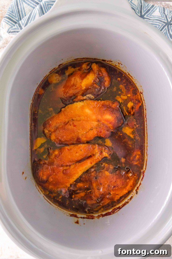 chicken breasts covered in hot honey sauce in a slow cooker