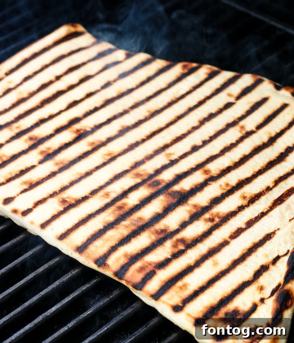 How to Make Grilled Pizza - Rolled out pizza dough on a baking sheet, ready for the grill.