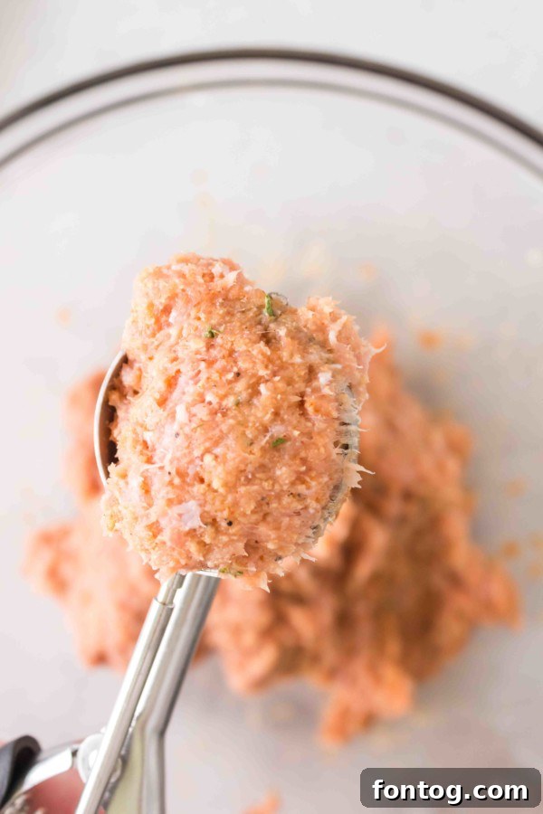 Scooping gluten-free baked turkey meatballs mixture with a cookie scoop