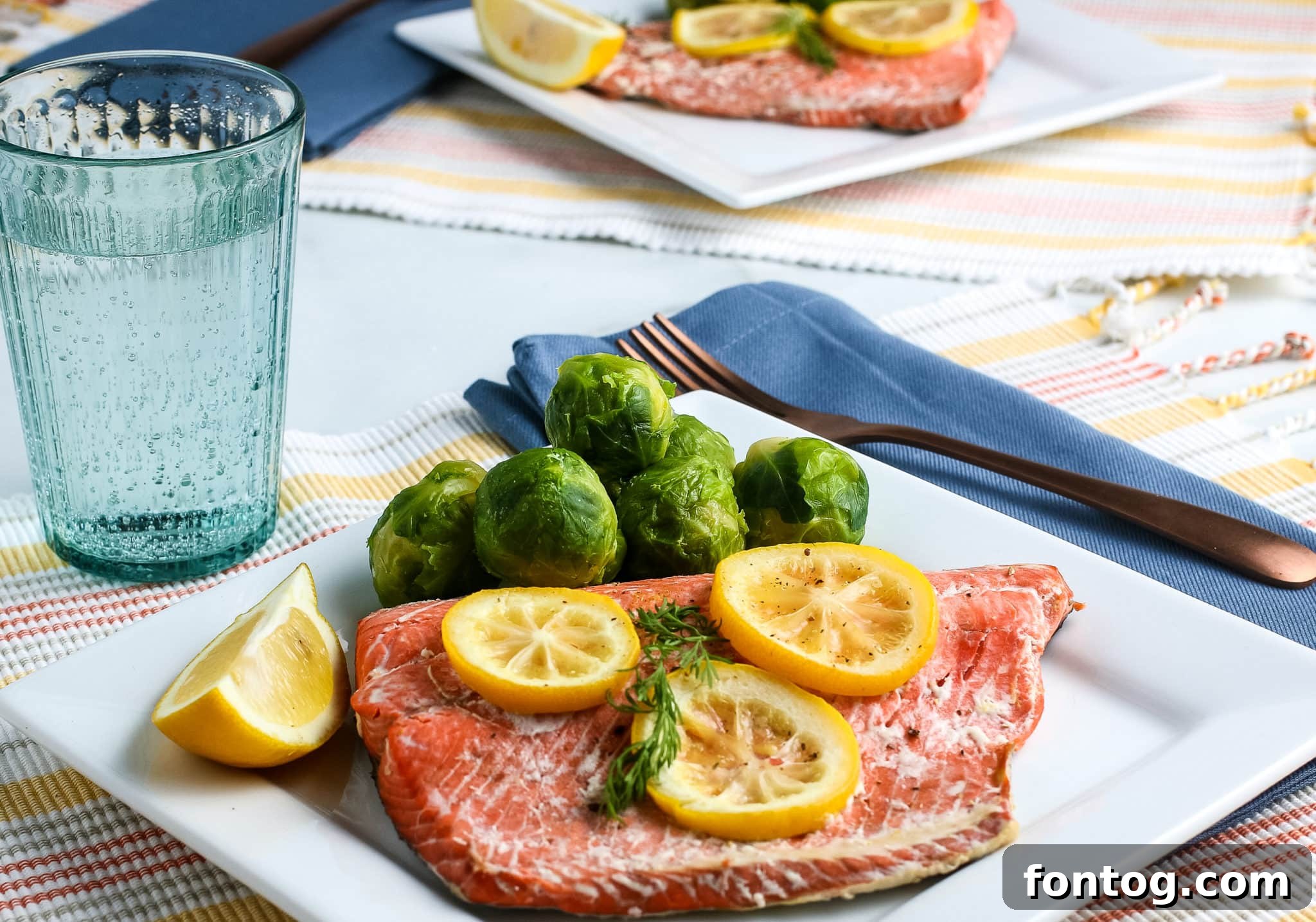 Cooked salmon on a platter with lemon slices.