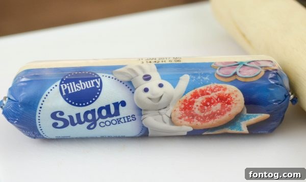 Two hands, likely a child's, pressing sugar cookie dough into a muffin tin for cookie cups