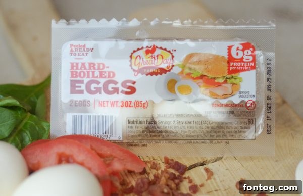 Sweet Potato Toast with a base of hummus, topped with sliced hard-boiled eggs, fresh spinach, and a sprinkle of shredded bacon.
