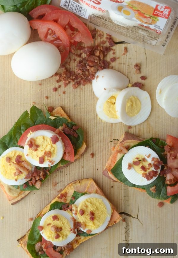 Sweet Potato Toast prepared and ready to eat, topped with egg, spinach, and tomato slices.