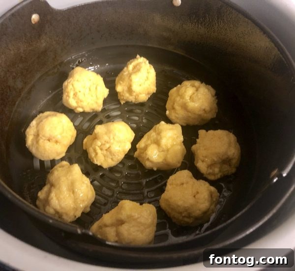 Air fried hush puppies cooking in an air fryer basket, becoming golden