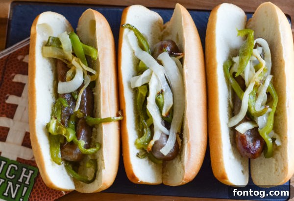 Close-up of air fryer basket containing sliced onions, green peppers, and Johnsonville Beer Brats