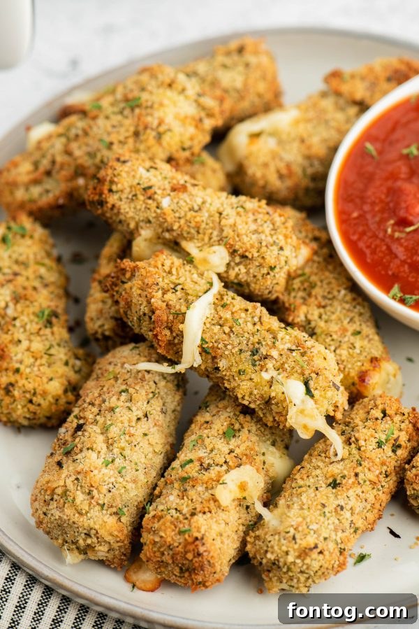 Golden & Gooey: Ninja Foodi Gluten-Free Mozzarella Sticks 2 Crispy Ninja Foodi Mozzarella Sticks served with marinara sauce.