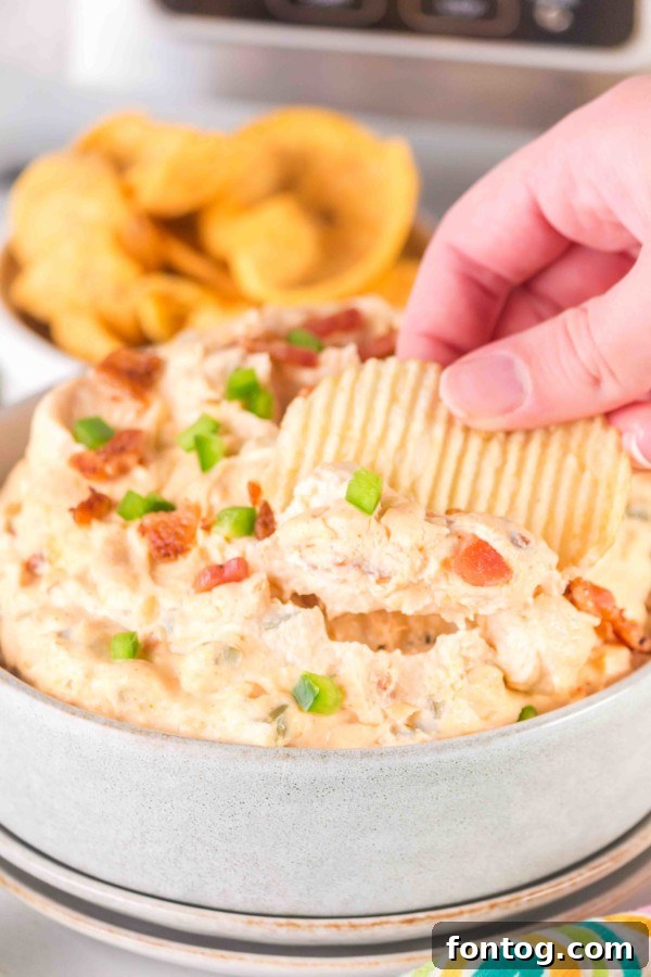 slow cooker jalapeno popper dip with a chip to serve