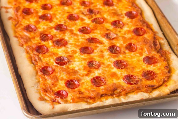 Close-up of a freshly baked sheet pan pizza, ready to be sliced.