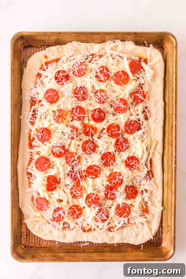 All the ingredients for sheet pan pizza laid out on a kitchen counter.